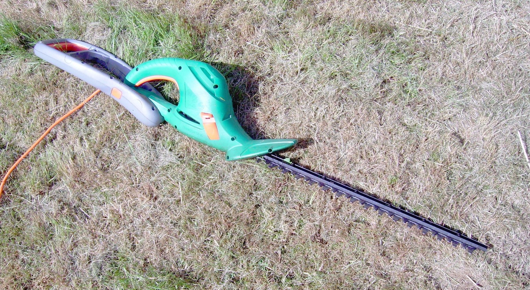 Heggenschaar met een lang handvat op het gras